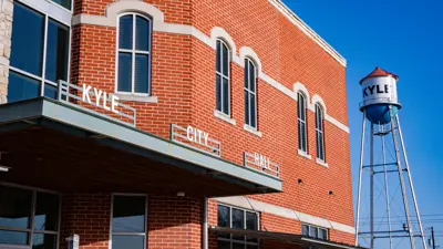 A photo of Kyle City Hall with the 'Kyle' water tower in the background on a clear day with blue skies.