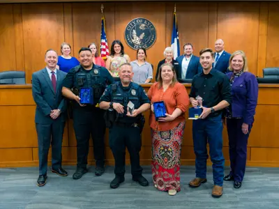 A group of people stand together in Kyle City Council Chambers to honor the Employees of the Quarter. 