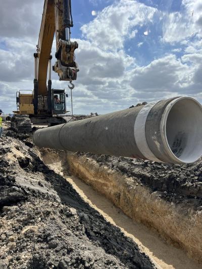Segment of the Alliance Water Pipeline being lifted by a crane and laid into the ground.