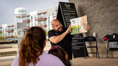 A Kyle Public LIbrary staff member reads a story to a child at a Storytime in the Park event. 